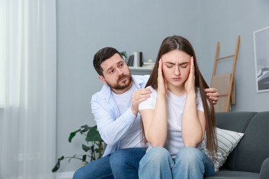 Photo of Man comforting his resentful girlfriend on couch at home