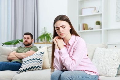 Resentful couple sitting on couch at home, selective focus