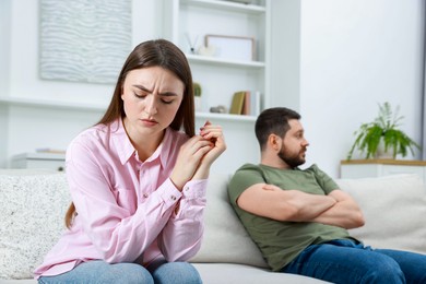 Resentful couple sitting on couch at home, selective focus