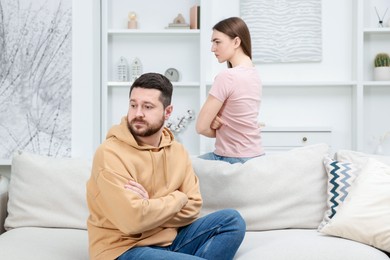 Photo of Resentful couple with crossed arms sitting on couch at home