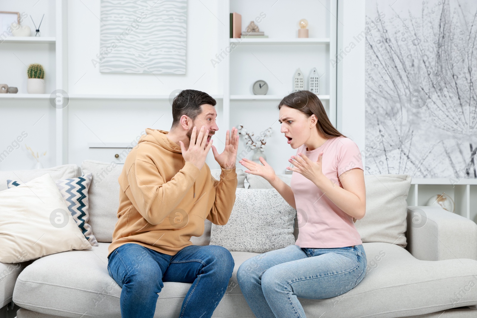 Photo of Angry couple arguing on couch at home