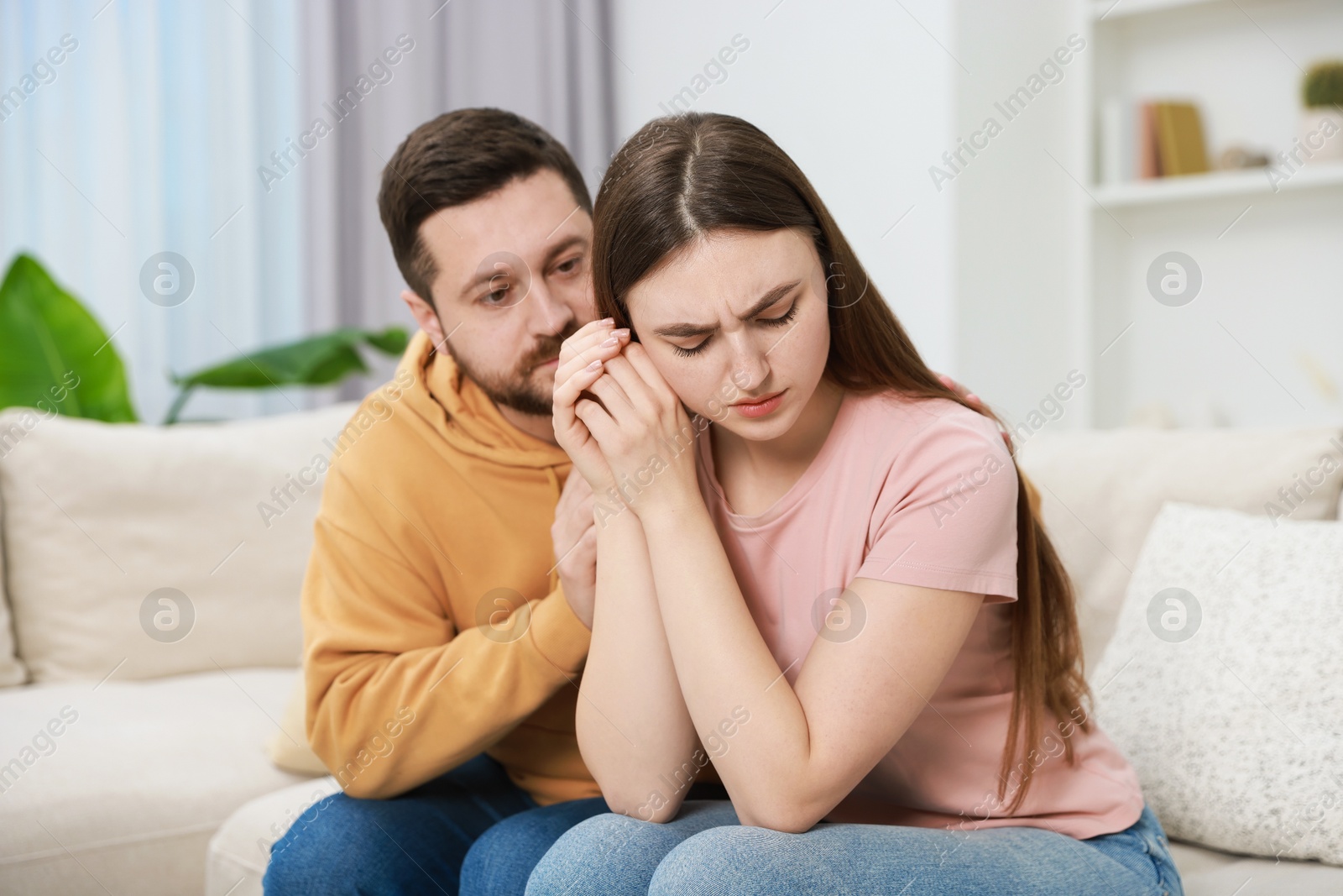 Photo of Man comforting his resentful girlfriend on couch at home