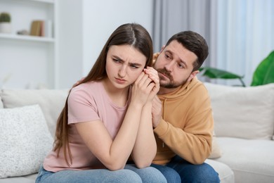 Photo of Man comforting his resentful girlfriend on couch at home