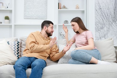 Photo of Angry couple arguing on couch at home