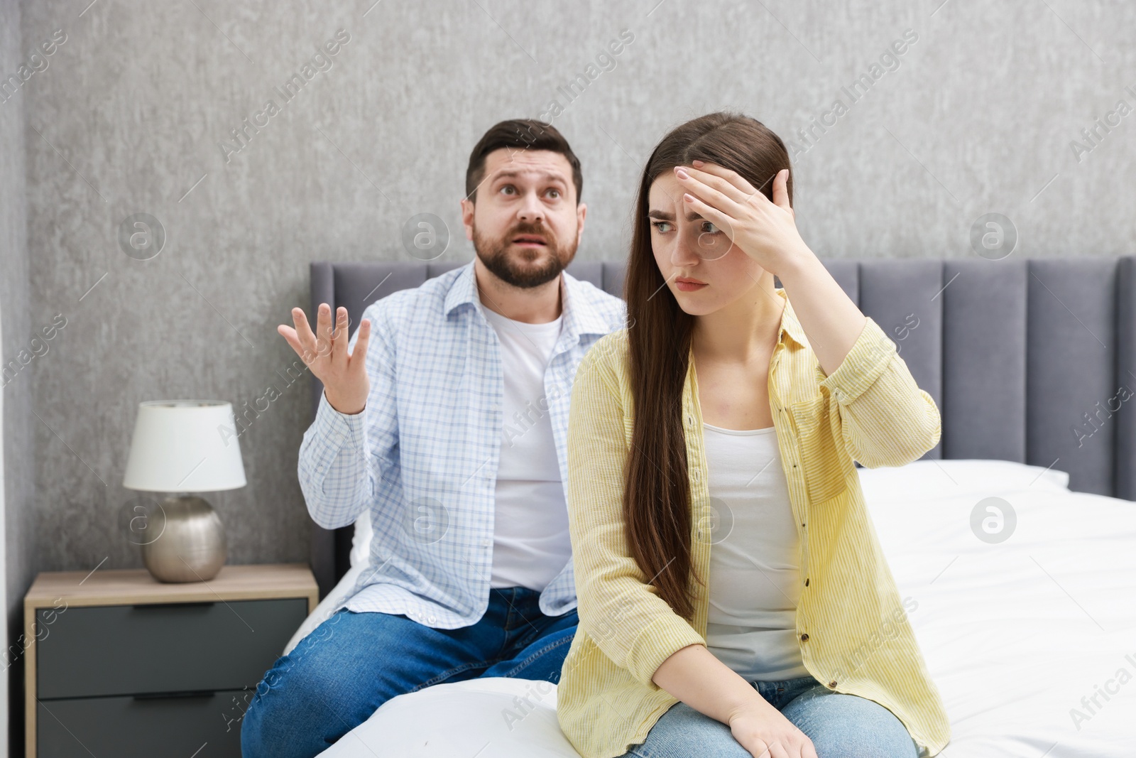 Photo of Angry couple arguing on bed at home