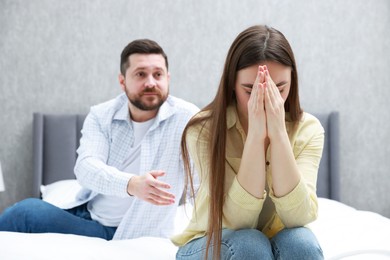 Photo of Resentful couple arguing on bed at home, selective focus