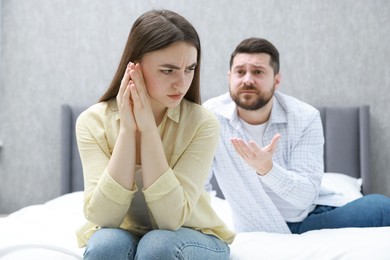 Photo of Resentful couple arguing on bed at home, selective focus