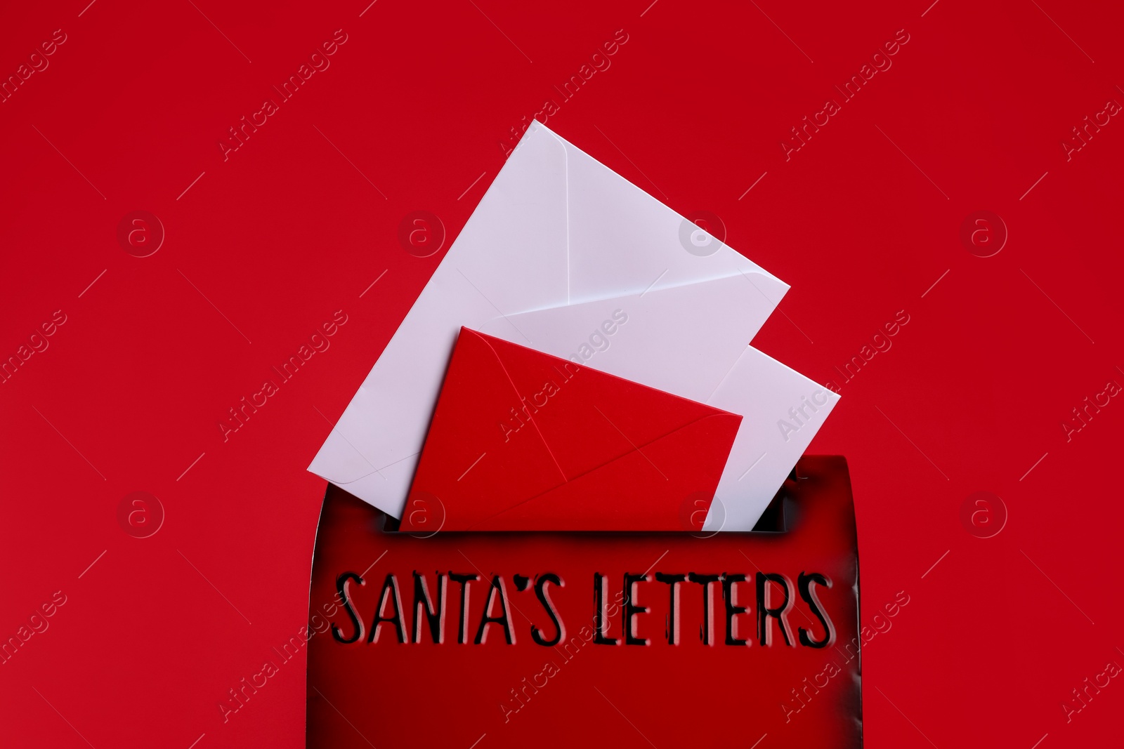 Photo of Santa Claus mailbox with letters on red background, closeup. Christmas tradition