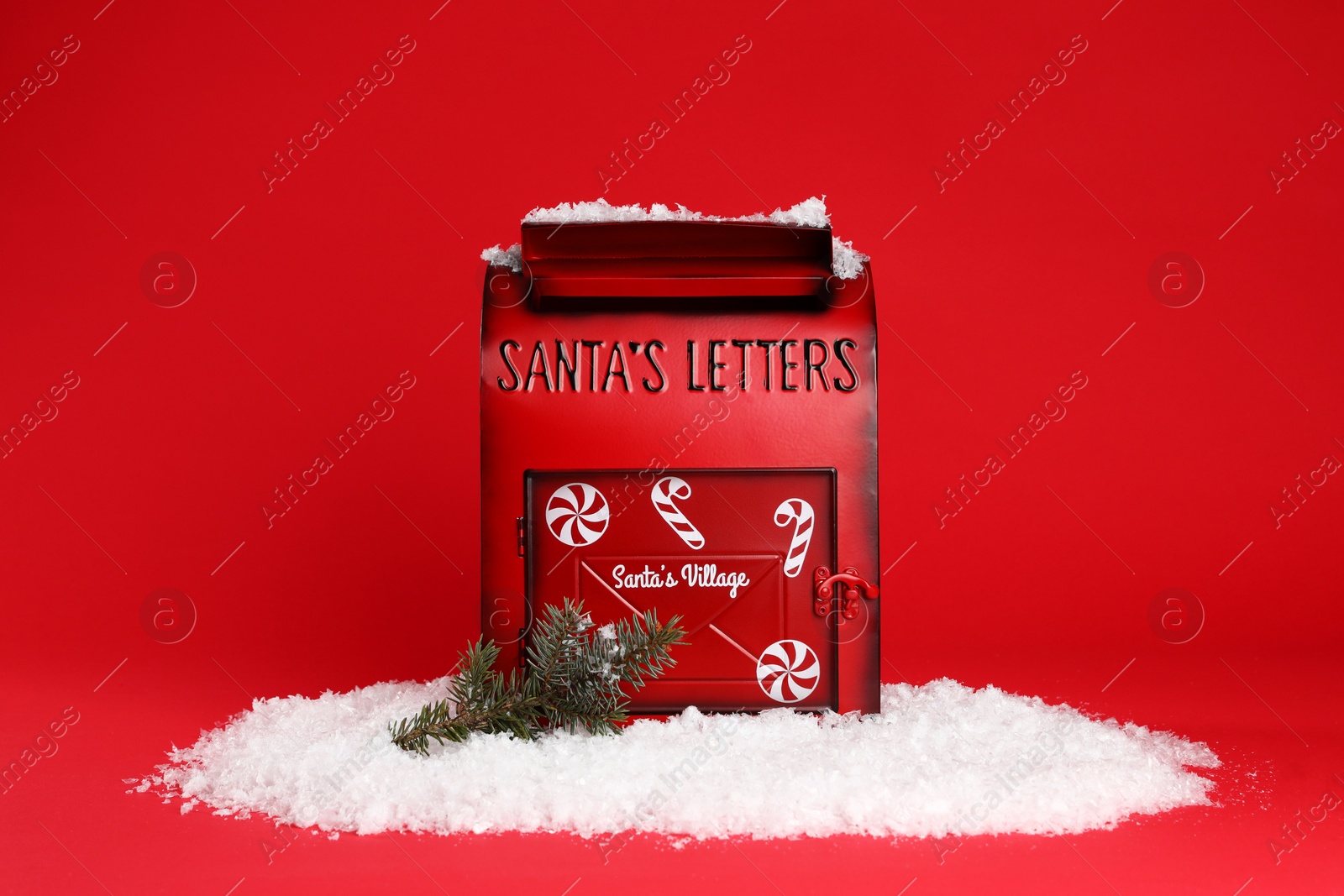 Photo of Santa Claus mailbox, fir tree branch and artificial snow on red background. Christmas tradition