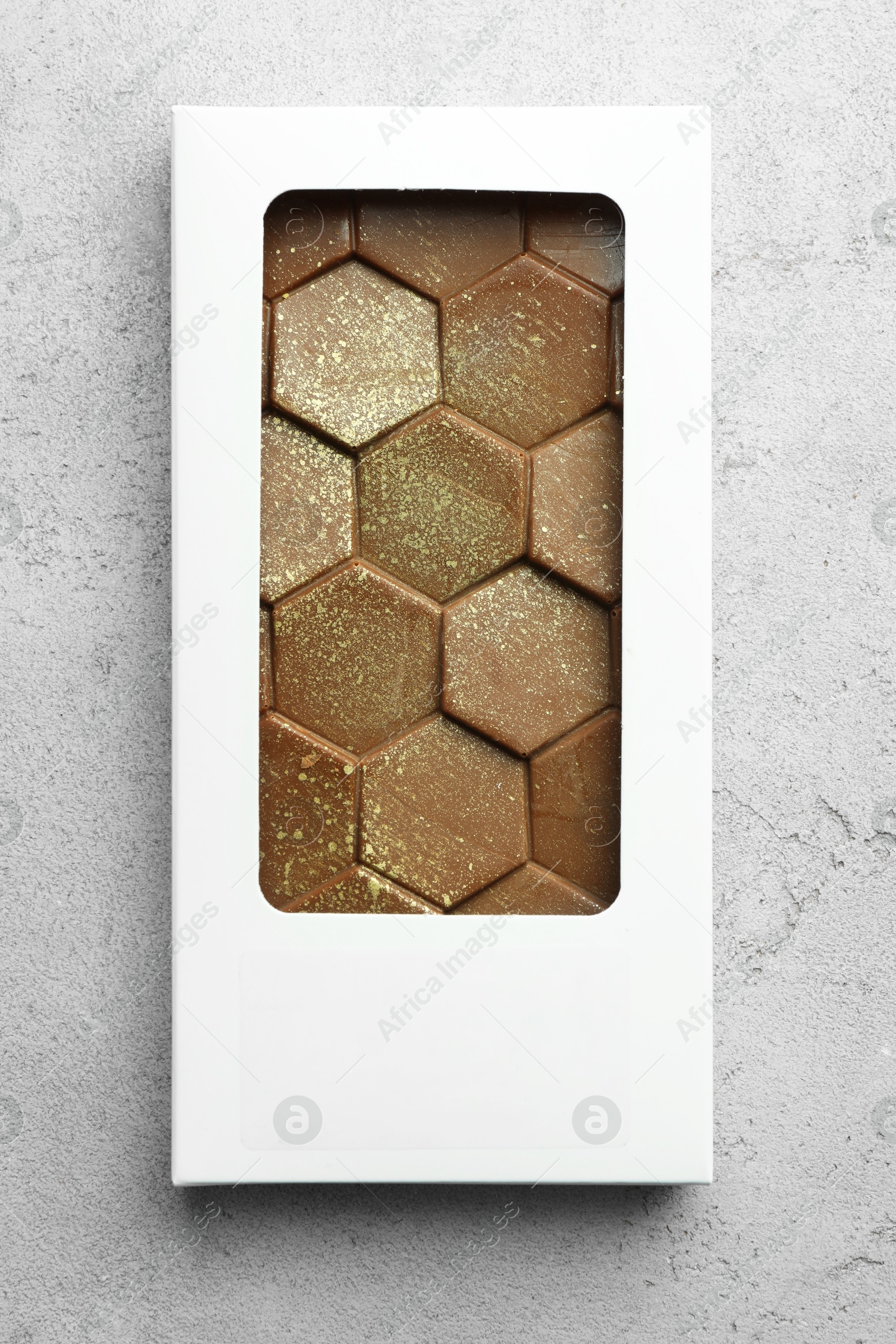 Photo of Tasty Dubai chocolate bar in package with pistachios and knafeh on textured table, top view. Space for text