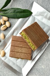 Photo of Pieces of tasty Dubai with pistachios and knafeh on grey textured table, flat lay