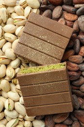 Photo of Pieces of tasty Dubai chocolate with knafeh, pistachios and cocoa beans, top view