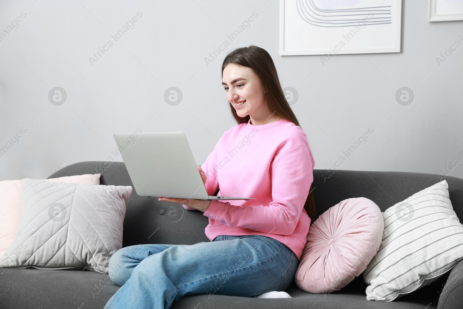 Photo of Smiling young woman working on laptop at home