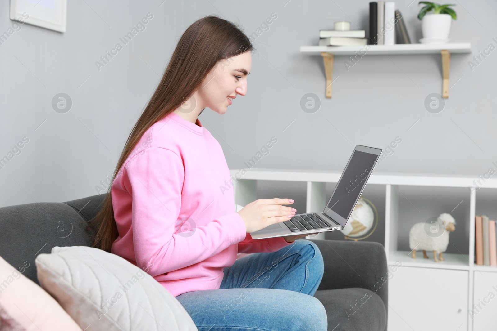 Photo of Smiling young woman working on laptop at home