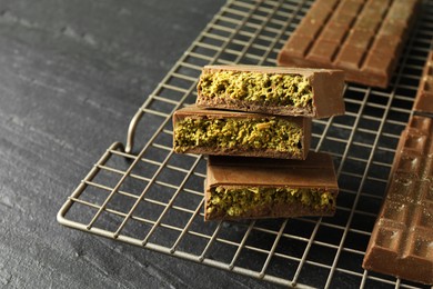 Photo of Pieces of delicious Dubai chocolate with pistachios and knafeh on black table, closeup