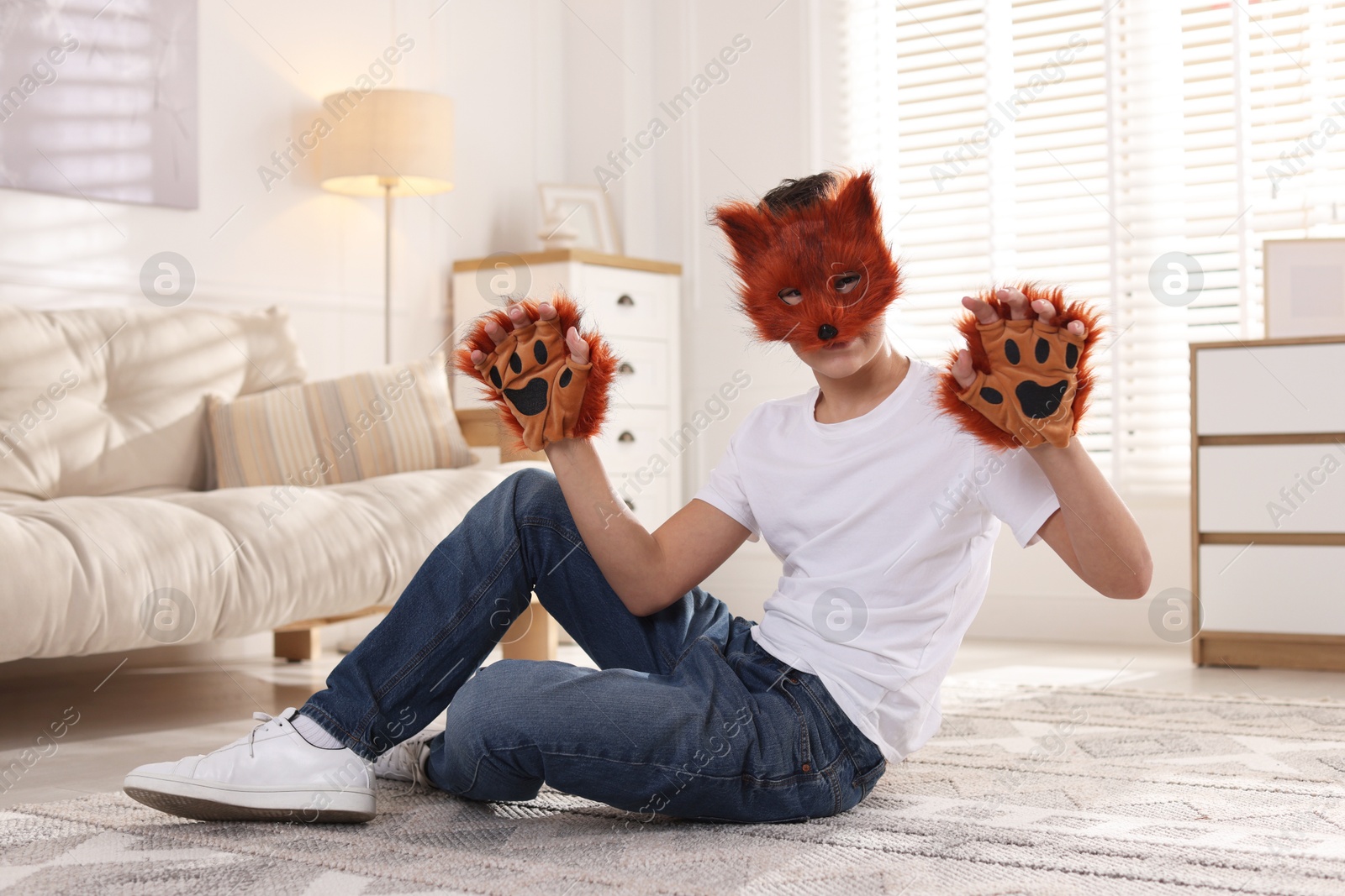 Photo of Quadrobics. Boy wearing fox mask and gloves on floor at home