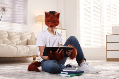 Photo of Quadrobics. Boy in fox mask, gloves and tail reading book at home