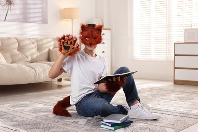 Photo of Quadrobics. Boy in fox mask, gloves and tail reading book at home