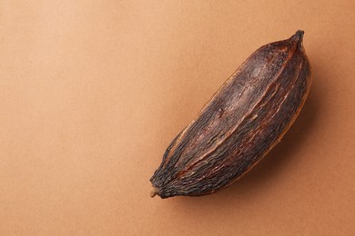 Photo of Cocoa pod on brown background, top view