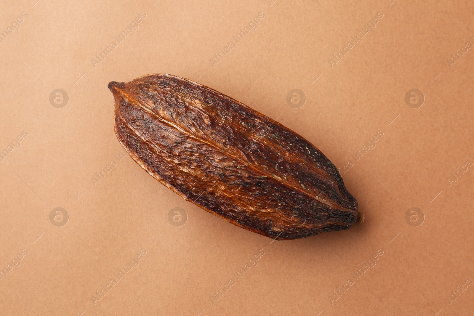 Photo of Cocoa pod on brown background, top view