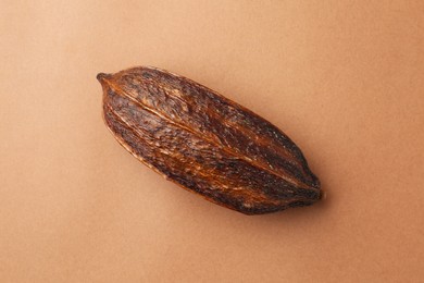 Cocoa pod on brown background, top view