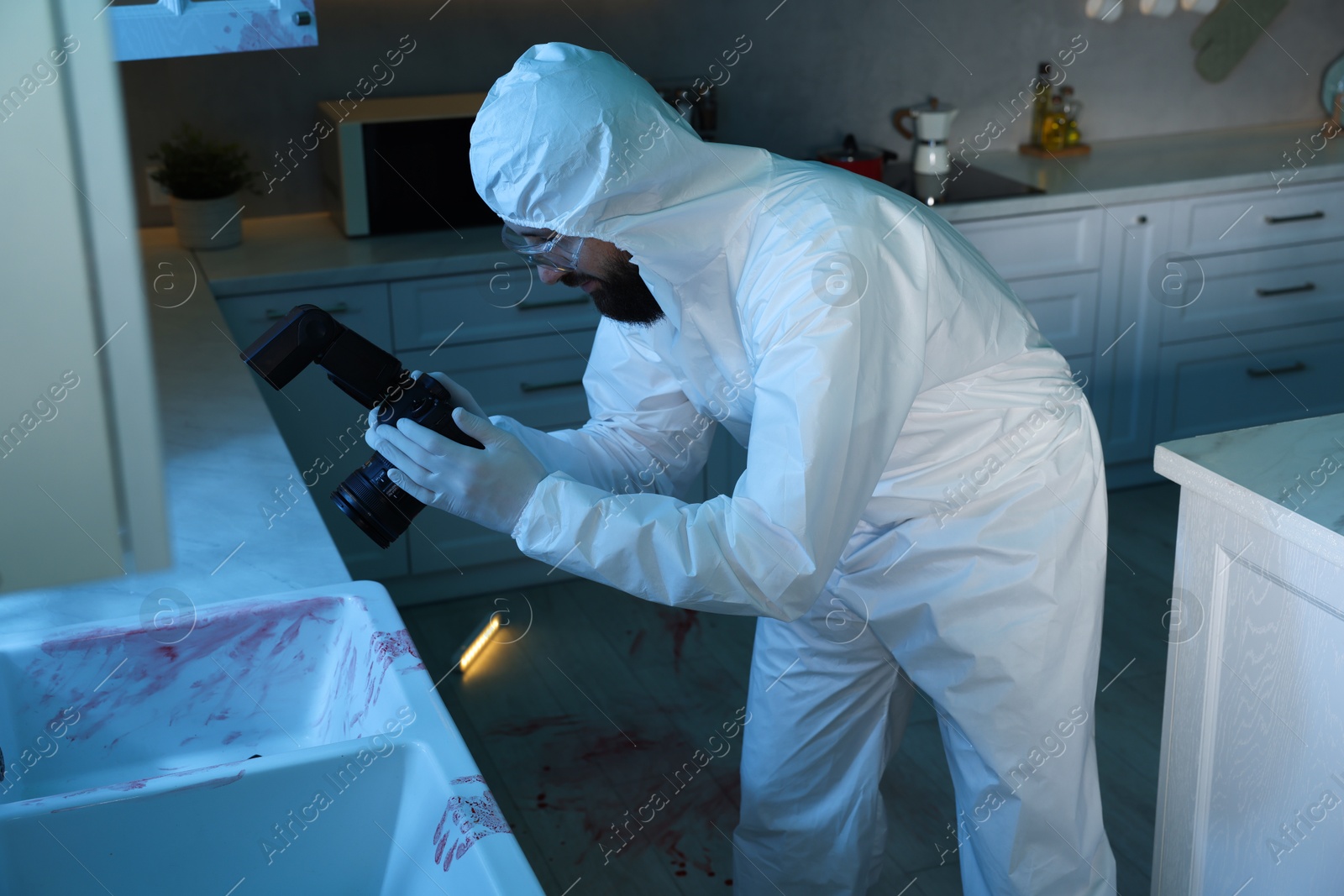 Photo of Forensic expert with camera working at crime scene indoors