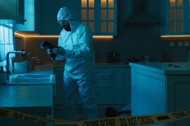 Photo of Forensic expert with camera working at crime scene in dark room