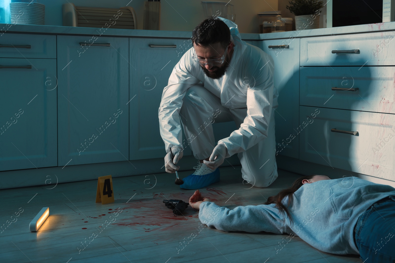 Photo of Forensic expert taking fingerprints with brush from gun and dead body at crime scene indoors