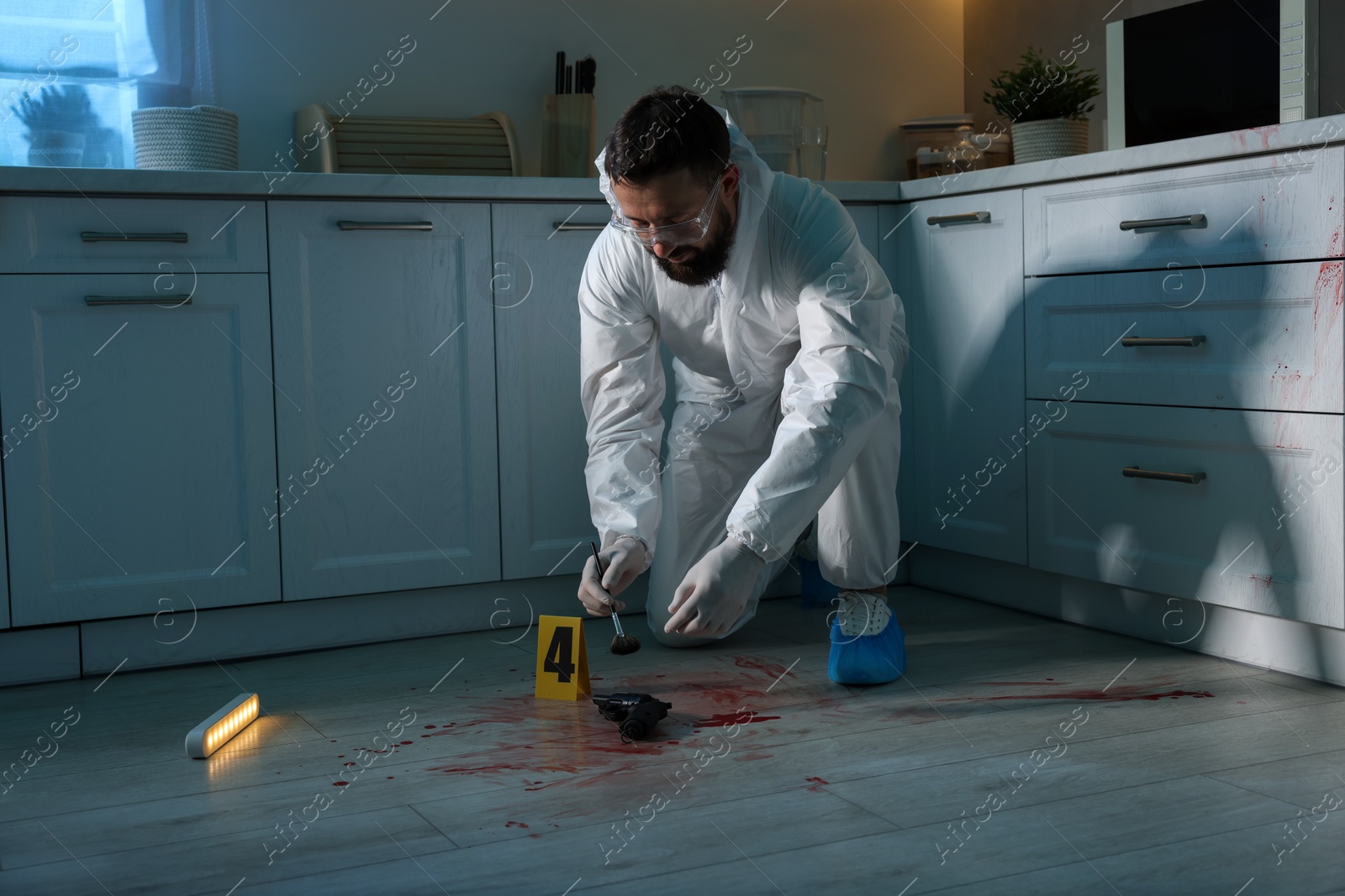 Photo of Forensic expert taking fingerprints with brush from gun at crime scene indoors