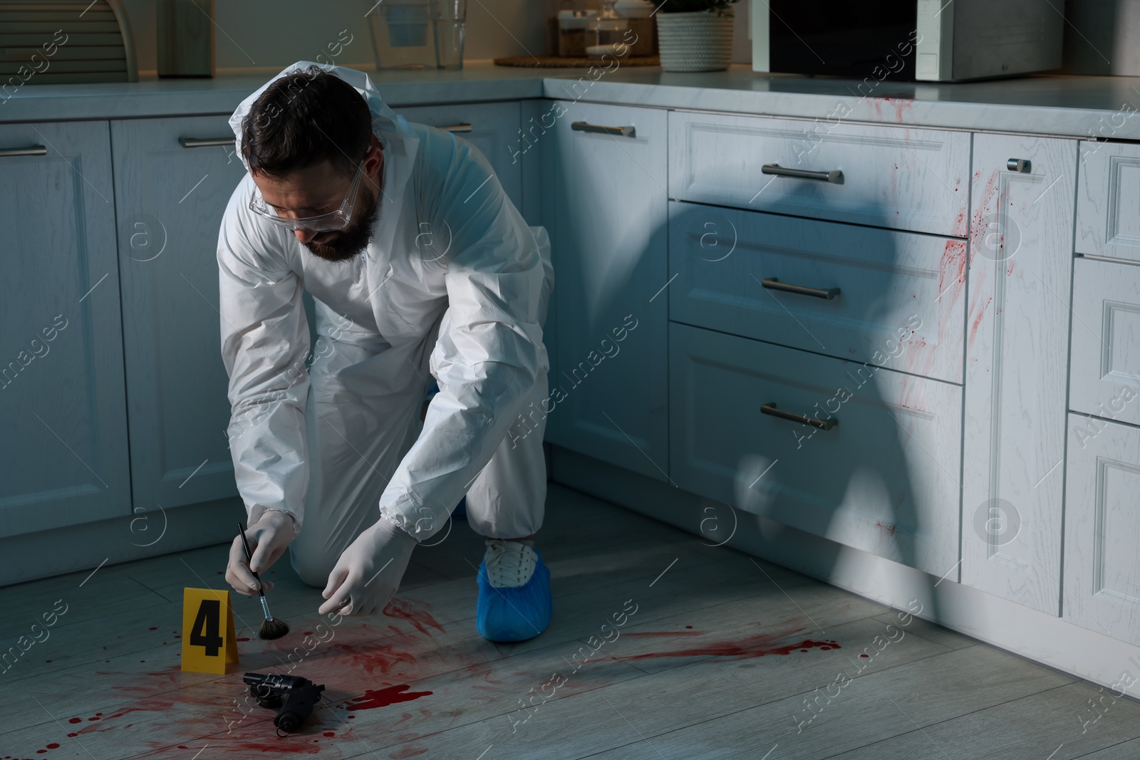 Photo of Forensic expert taking fingerprints with brush from gun at crime scene indoors