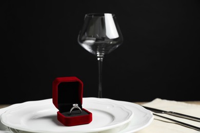 Photo of Beautiful setting for romantic dinner and engagement ring on wooden table