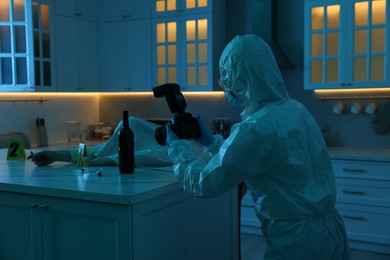 Photo of Forensic expert with camera working at crime scene and dead woman's body in dark room