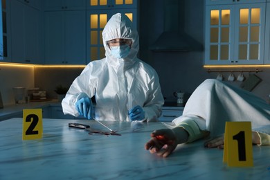 Photo of Forensic expert taking blood sample and dead woman's body at countertop indoors