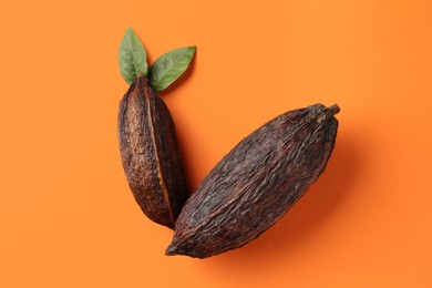 Photo of Natural cocoa pods on orange background, top view