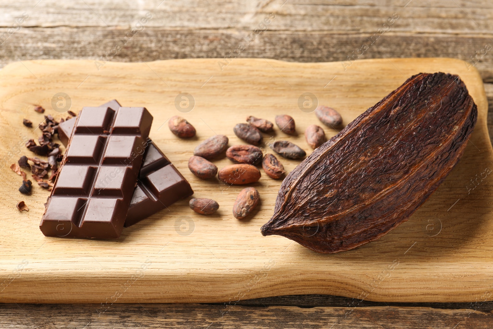 Photo of Cocoa pod, beans and chocolate on wooden table, closeup