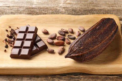 Cocoa pod, beans and chocolate on wooden table, closeup