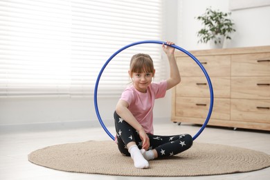 Photo of Cute little girl with hula hoop on floor at home