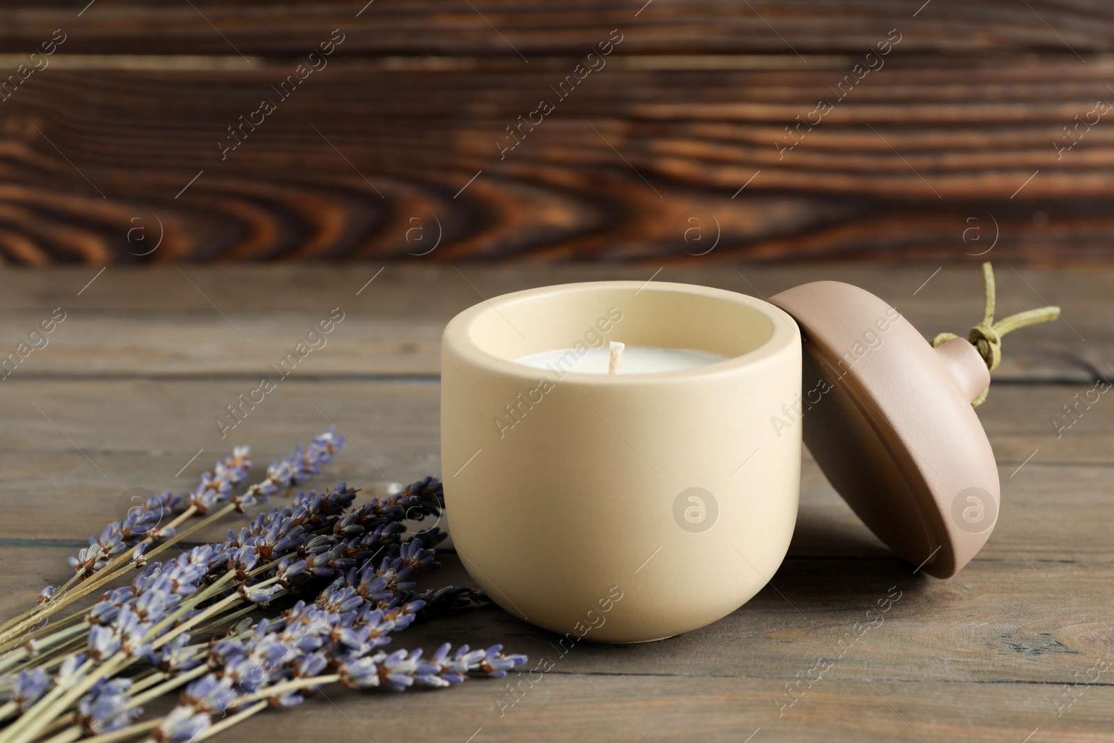 Photo of Soy wax candle, lid and lavender flowers on wooden table, space for text