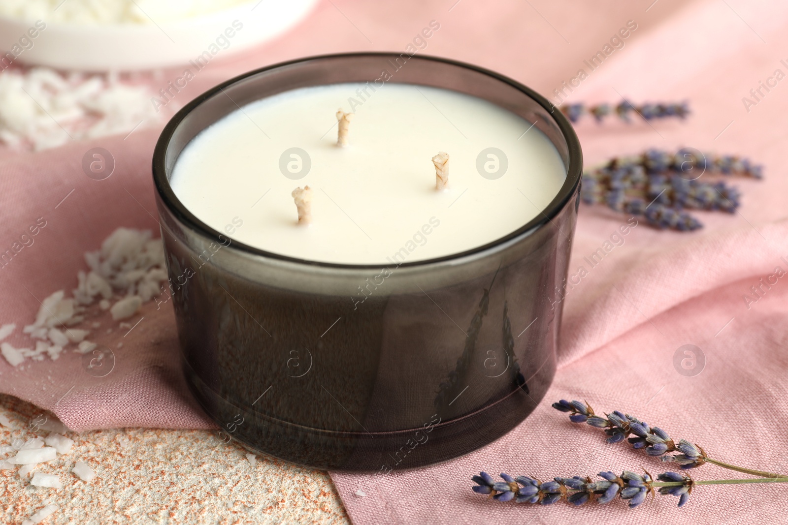 Photo of Soy wax candle, pink napkin and lavender flowers on table, closeup