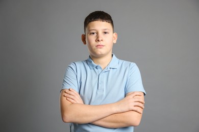 Photo of Portrait of teenage boy with crossed arms on grey background