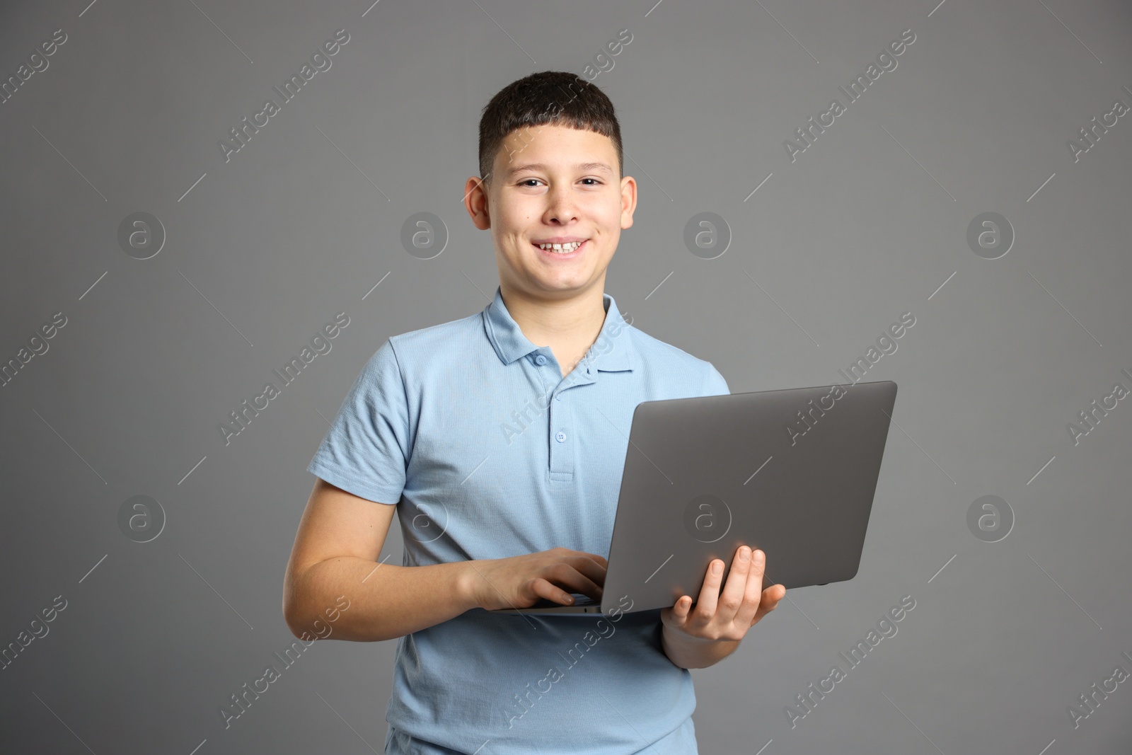 Photo of Portrait of teenage boy with laptop on grey background