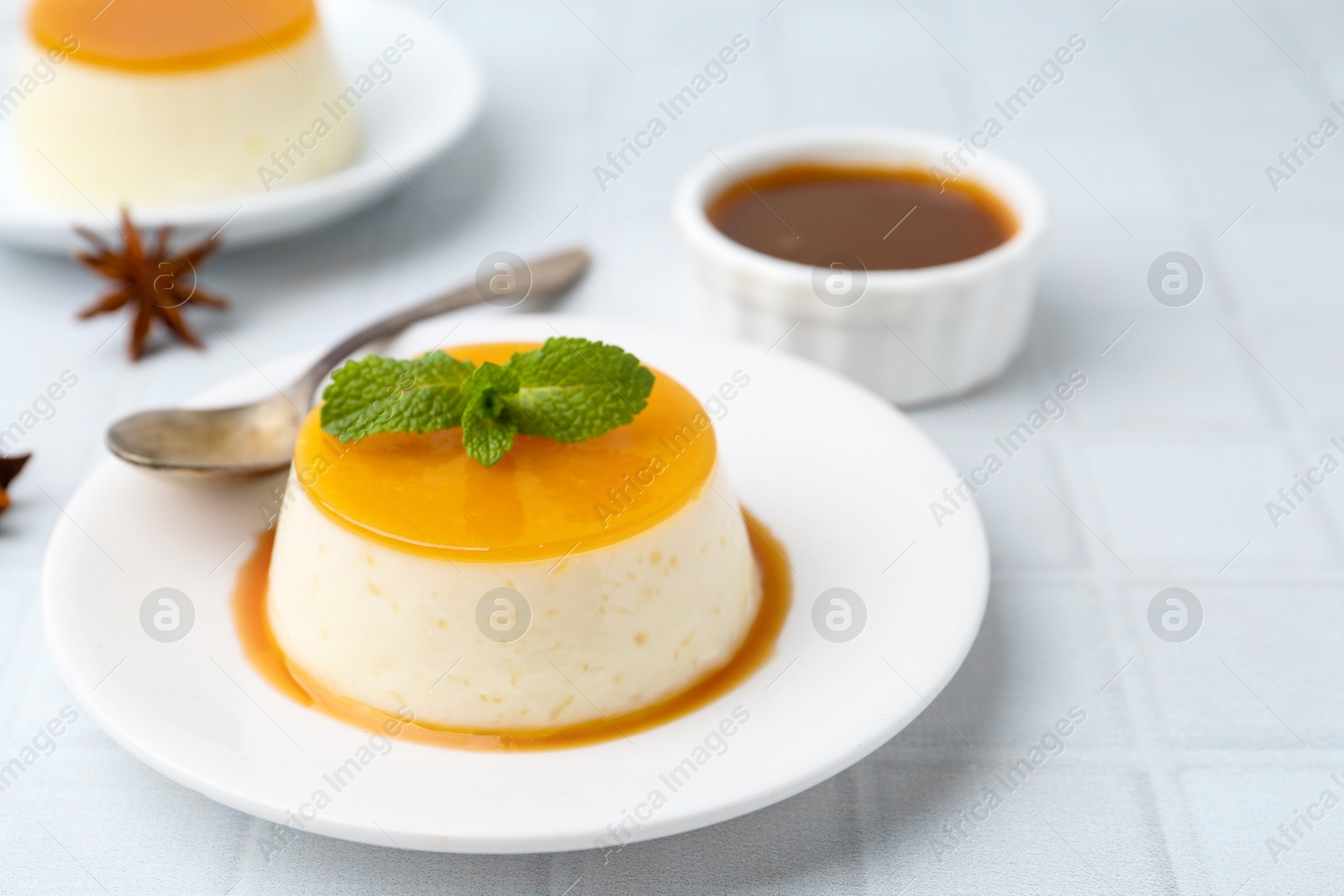 Photo of Tasty pudding with caramel sauce served on white tiled table, closeup. Space for text