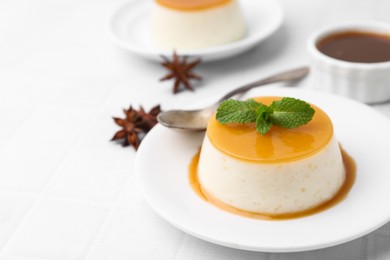 Photo of Tasty pudding with caramel sauce served on white tiled table, closeup. Space for text