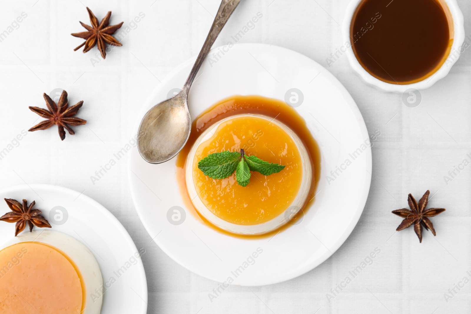 Photo of Tasty pudding with caramel sauce served on white tiled table, flat lay