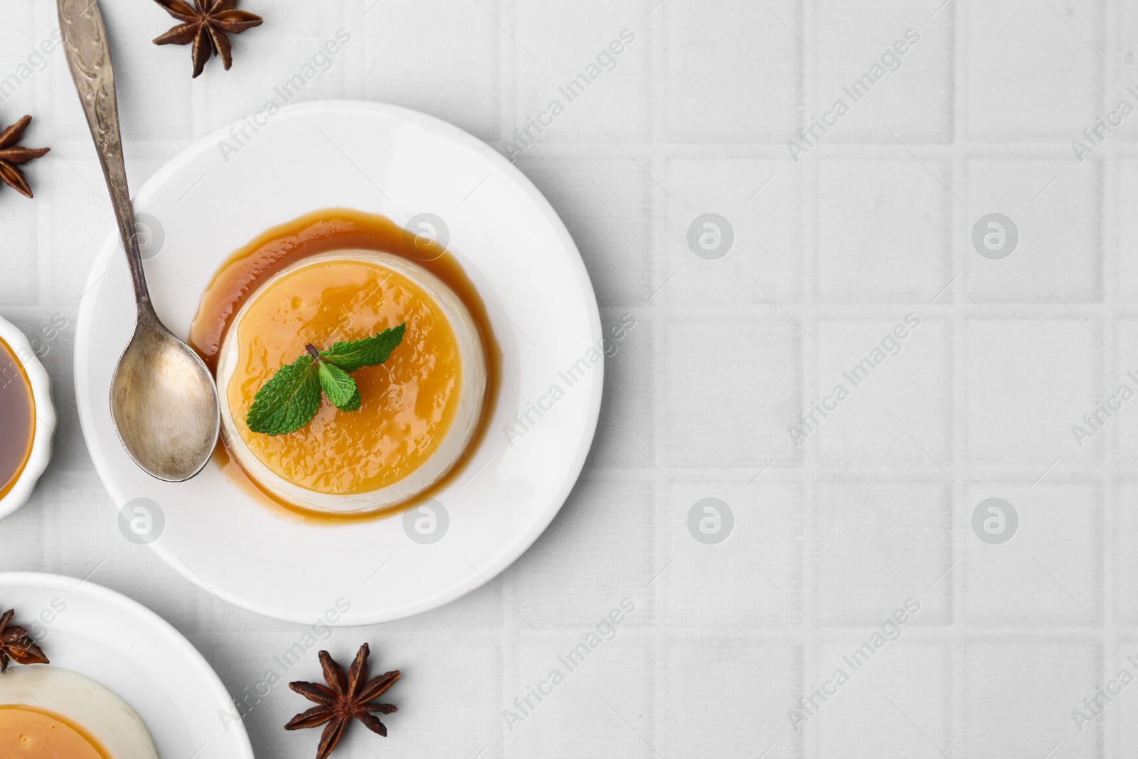 Photo of Tasty pudding with caramel sauce served on white tiled table, flat lay. Space for text