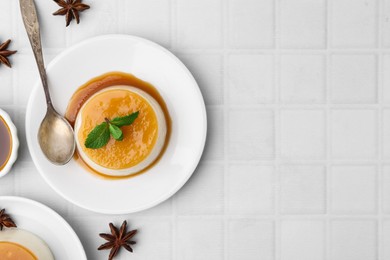 Photo of Tasty pudding with caramel sauce served on white tiled table, flat lay. Space for text