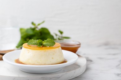 Photo of Tasty pudding with caramel sauce served on white marble table, closeup. Space for text