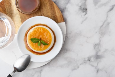 Photo of Tasty pudding with caramel sauce served on white marble table, top view. Space for text