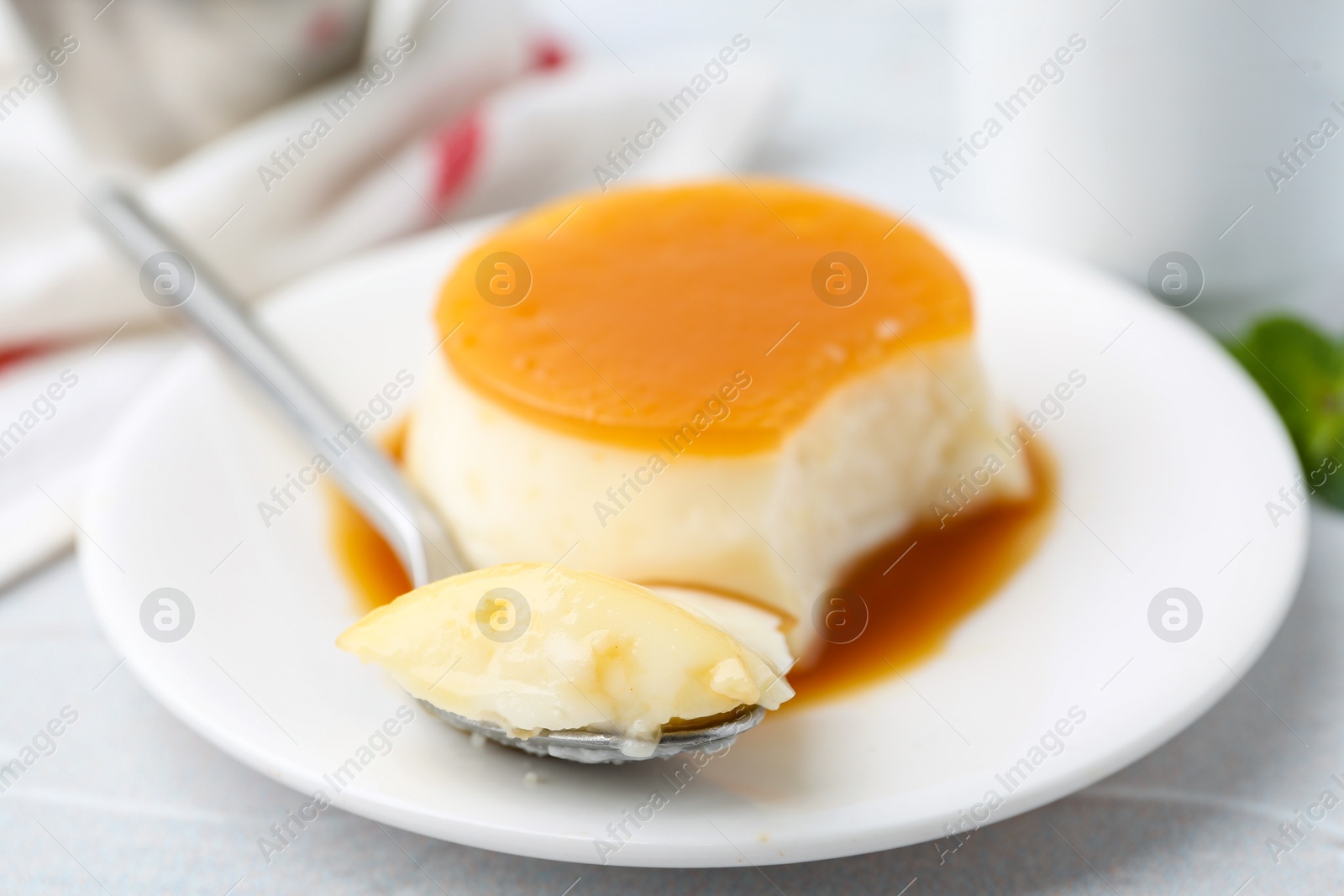 Photo of Tasty pudding with caramel sauce served on white textured table, closeup