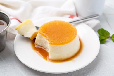 Photo of Tasty pudding with caramel sauce served on white textured table, closeup